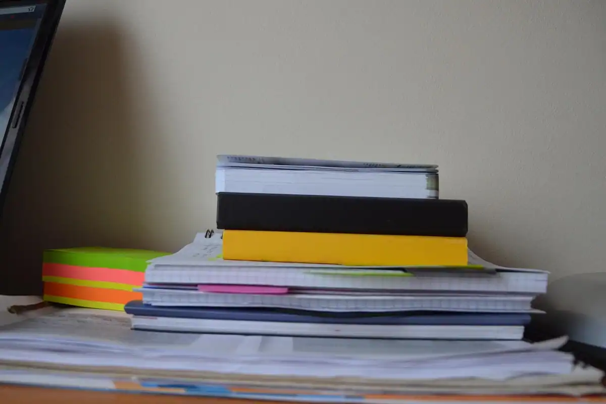 Stive de hârtii și caiete pe un birou, dosare pregătite pentru evaluare