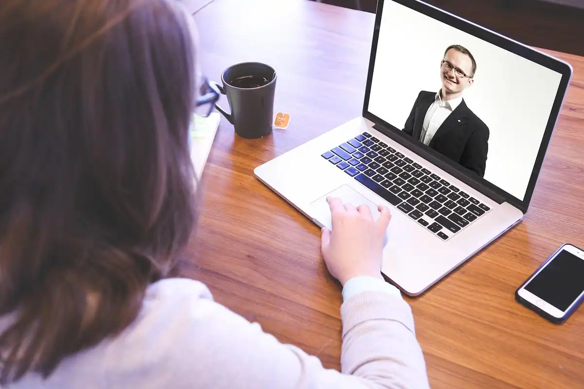 Femeie care urmărește pe laptop un interlocutor în timpul unui apel video