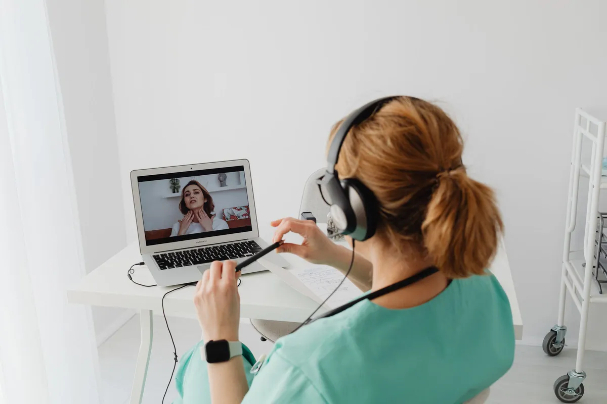 Specialistă cu cască pe urechi, la laptop, în timpul unei consultații video