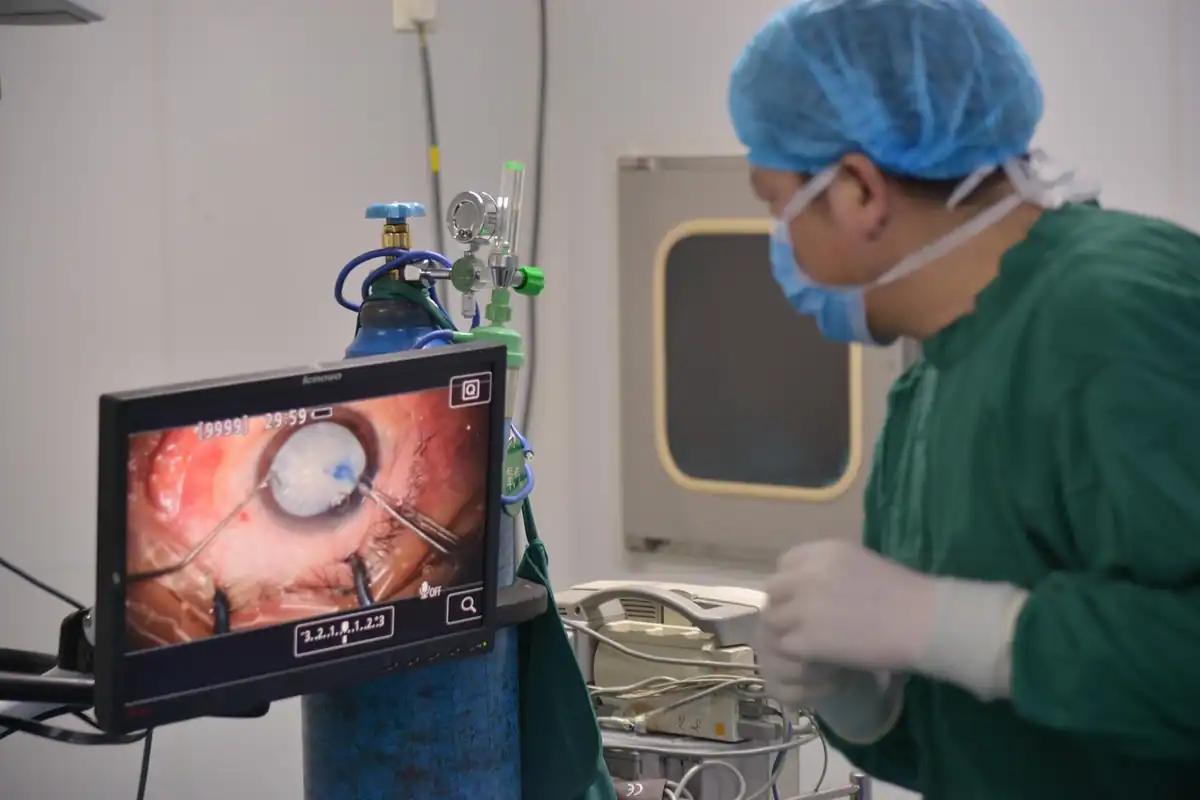Asistent medical cu bonetă lângă un monitor cu imagine endoscopică