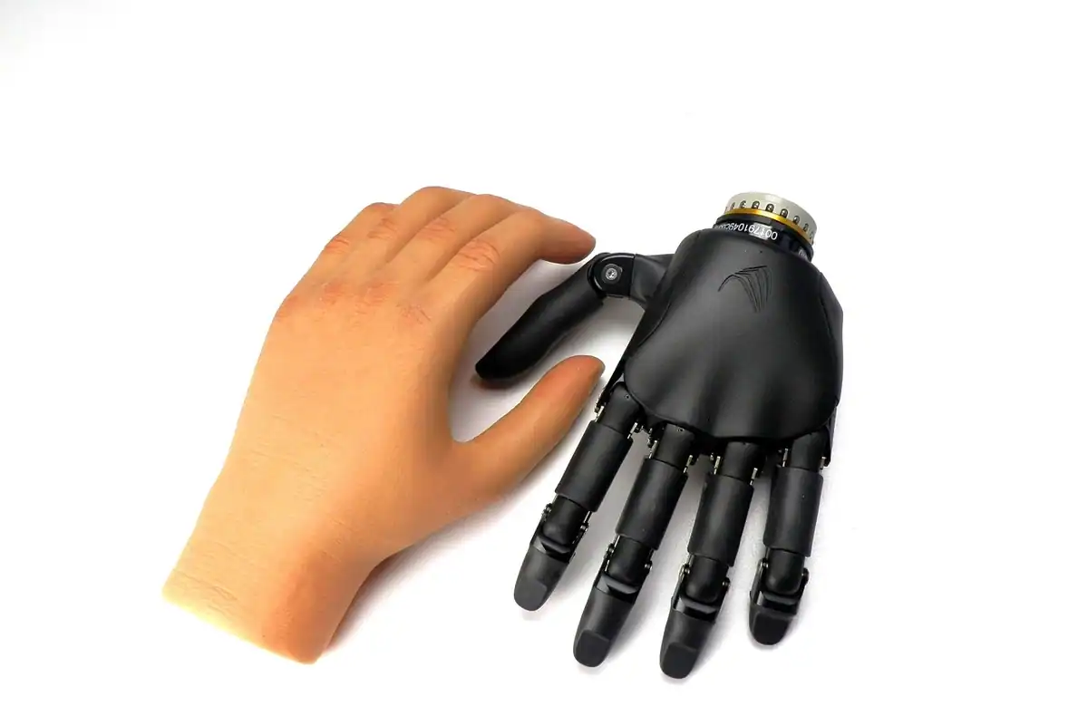 Mână artificială neagră așezată lângă o mână naturală