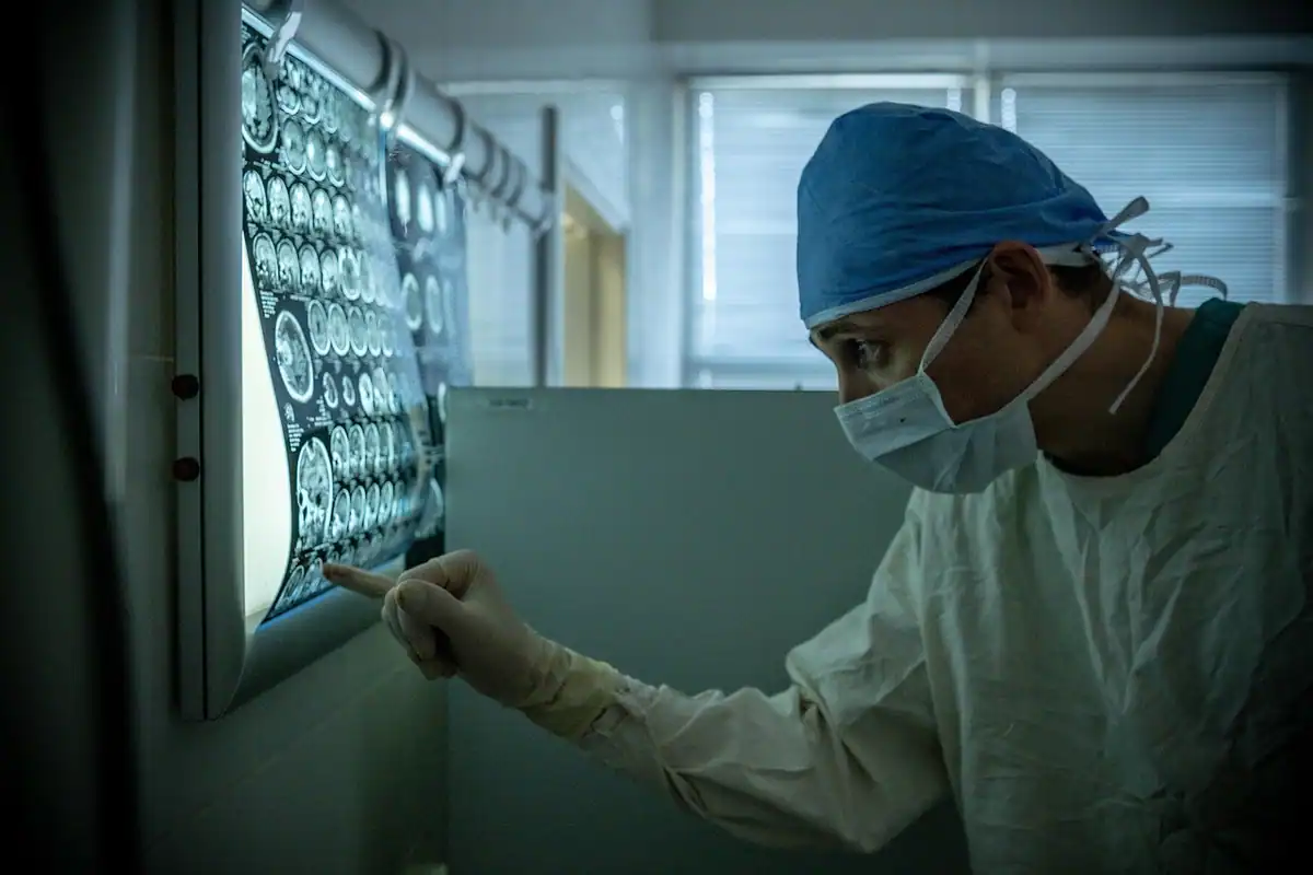Medic cu bonetă privește radiografii montate pe un negatoscop
